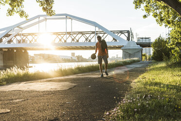 Junger Mann dribbelt Basketball am Fluss - UUF11160