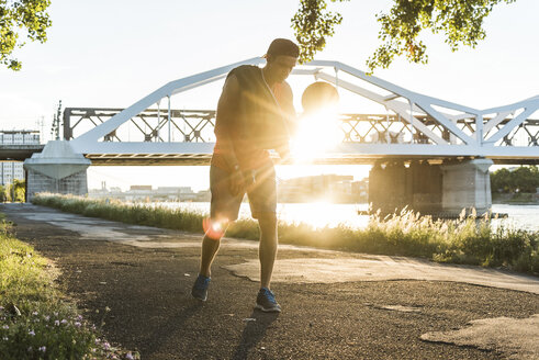 Young man dribbling basketball at the river - UUF11161