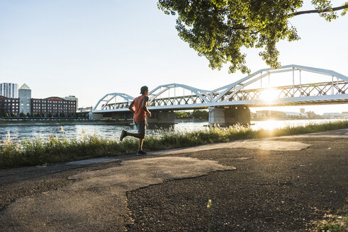 Young man dribbling basketball at the river - UUF11162