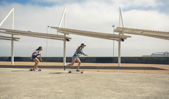 Zwei junge Frauen beim Longboarden auf der Strandpromenade - DAPF00776