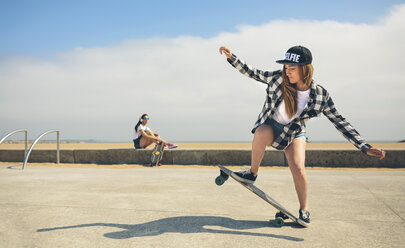 Junge Frau beim Longboarden, während ihr Freund sie beobachtet - DAPF00779