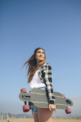 Porträt einer jungen Frau mit Longboard, lizenzfreies Stockfoto