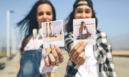 Zwei junge Frauen zeigen Sofortfotos mit ihren Longboards - DAPF00789