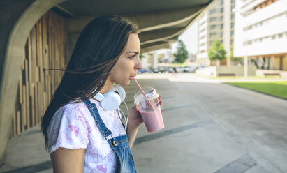 Young woman with headphones drinking strawberry smoothie - DAPF00791