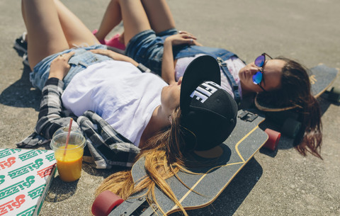 Zwei junge Frauen mit Longboards genießen den Sommer, lizenzfreies Stockfoto