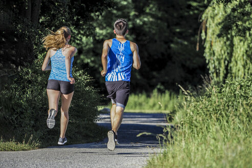 Rückenansicht eines jungen Paares beim Joggen im Park - STSF01249