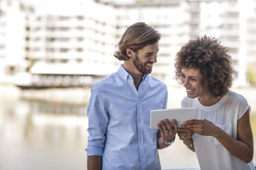 Businessman and woman having a meeting outdoors, using digital tablet - ZEF14134