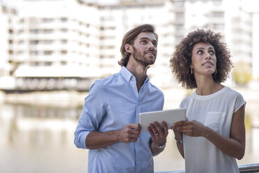 Businessman and woman having a meeting outdoors, using digital tablet - ZEF14135