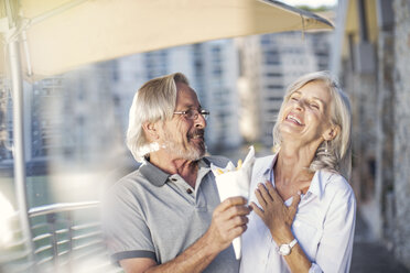 Senior couple taking a city break, eating French fries - ZEF14160
