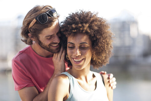 Happy young couple, man whispering into woman's ear - ZEF14184