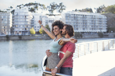 Happy couple standing at railing near water, having fun - ZEF14196