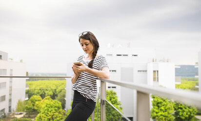 Frau benutzt Smartphone auf Balkon - HAPF01918