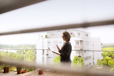 Frau mit Notizbuch auf Balkon stehend - HAPF01920