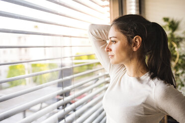 Woman at home looking out of the window - HAPF01938