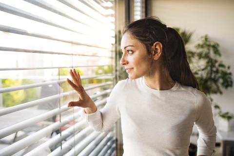 Frau zu Hause mit Blick aus dem Fenster, lizenzfreies Stockfoto