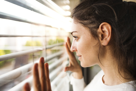 Frau zu Hause mit Blick aus dem Fenster, lizenzfreies Stockfoto