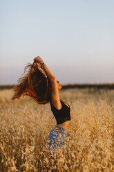 Young woman standing in grain field enjoying sunset - JPF00254