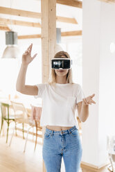 Young woman wearing VR goggles, designing her new home - GUSF00142