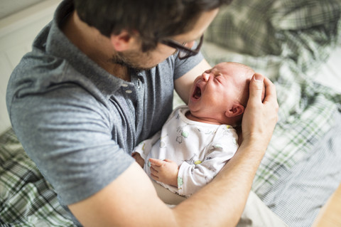 Vater zu Hause tröstet seine weinende kleine Tochter, lizenzfreies Stockfoto