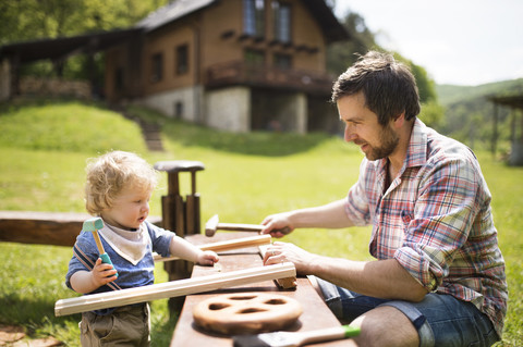 Father and little son working with hammer in garden stock photo