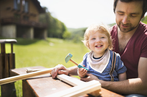 Father and little son working with hammer in garden stock photo