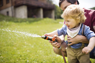 Kleiner Junge bewässert mit seinem Vater den Rasen - HAPF02000