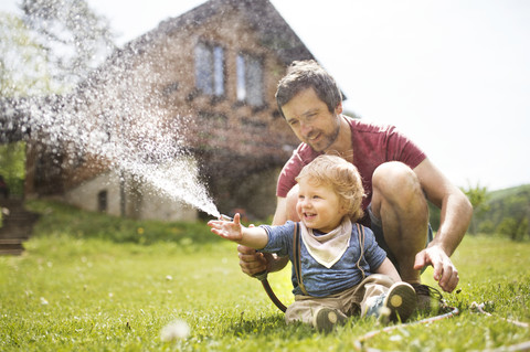 Little boy with his father watering the lawn stock photo