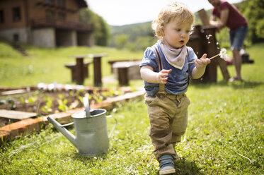 Junge im Garten mit Gießkanne und Vater im Hintergrund - HAPF02015