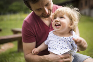 Father dressing his little son in the garden - HAPF02019