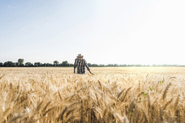 Ein älterer Landwirt prüft auf einem Feld die Ähren - UUF11167