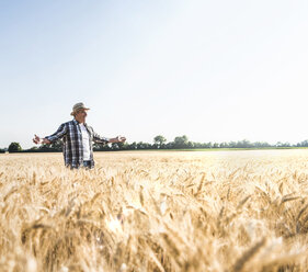 Happy senior farmer standing in wheat field - UUF11176