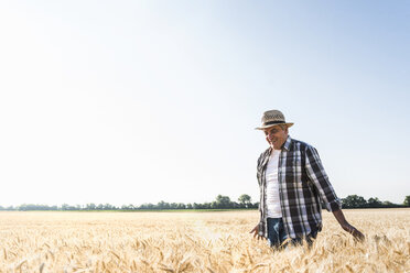 Happy senior farmer walking in wheat field - UUF11178