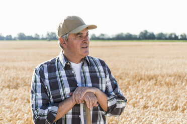 Portrait of senior farmer standing in front of a field looking at distance - UUF11180