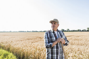 Senior farmer standing in front of wheat field watching something - UUF11181