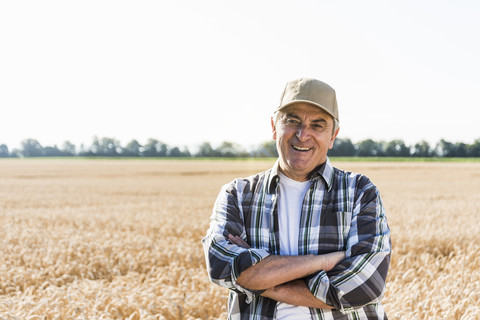 Porträt eines lachenden älteren Landwirts, der vor einem Feld steht, lizenzfreies Stockfoto