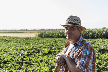 Portrait of smiling senior farmer standing in front of a field - UUF11194