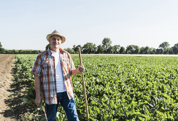 Porträt eines lächelnden älteren Landwirts, der vor einem Feld steht - UUF11199