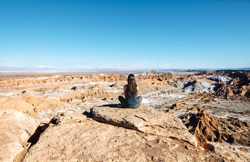 Chile, Atacama-Wüste, Rückenansicht einer Frau, die auf einem Felsen sitzt und die Aussicht betrachtet - GEMF01745