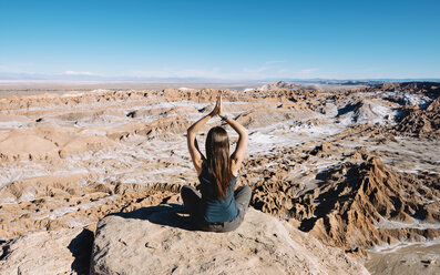Chile, Atacama-Wüste, Rückenansicht einer Frau, die auf einem Felsen Yoga übt - GEMF01746