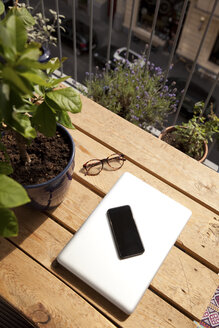 Smartphone, Laptop und Brille auf einer Palette auf dem Balkon - MFRF00886