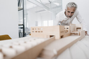 Älterer Geschäftsmann, der ein architektonisches Modell im Büro untersucht - KNSF02116