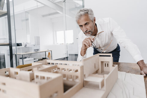 Älterer Geschäftsmann, der ein architektonisches Modell im Büro untersucht - KNSF02120