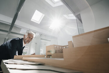 Älterer Geschäftsmann, der ein architektonisches Modell im Büro untersucht - KNSF02124