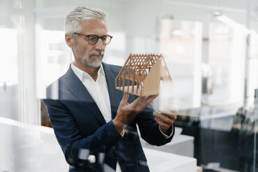 Mature businessman examining architectural model in office - KNSF02134