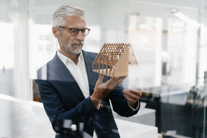 Älterer Geschäftsmann, der ein architektonisches Modell im Büro untersucht - KNSF02134