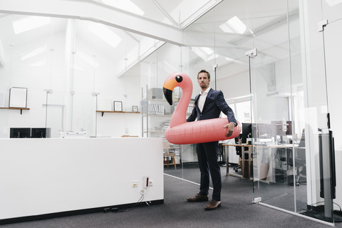 Geschäftsmann im Büro mit aufblasbarem Flamingo, lizenzfreies Stockfoto