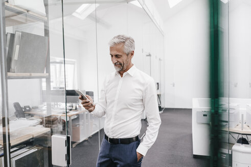 Älterer Geschäftsmann hält Handy im Büro - KNSF02139