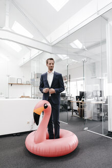 Geschäftsmann im Büro mit aufblasbarem Flamingo - KNSF02140