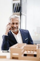 Mature businessman examining architectural model in office - KNSF02146