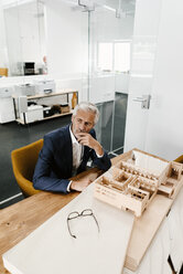 Mature businessman with architectural model in office - KNSF02152